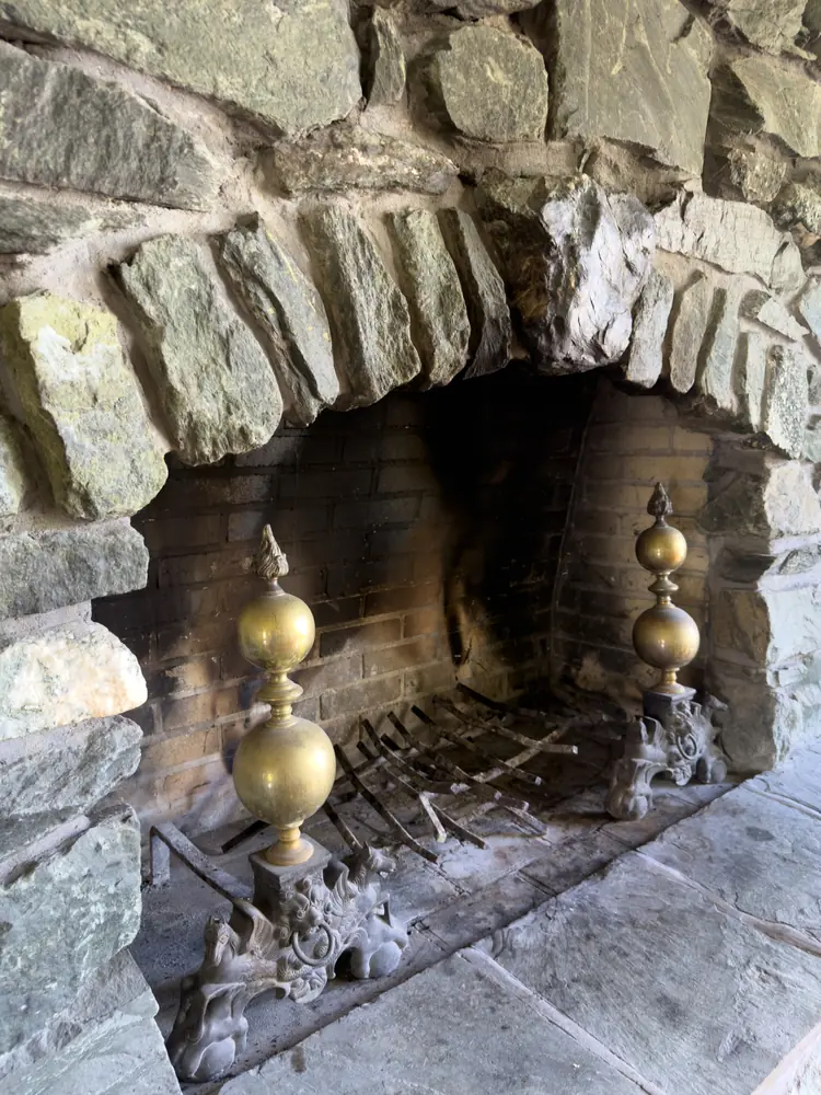 Close view of the fieldstone fireplace with brass andirons