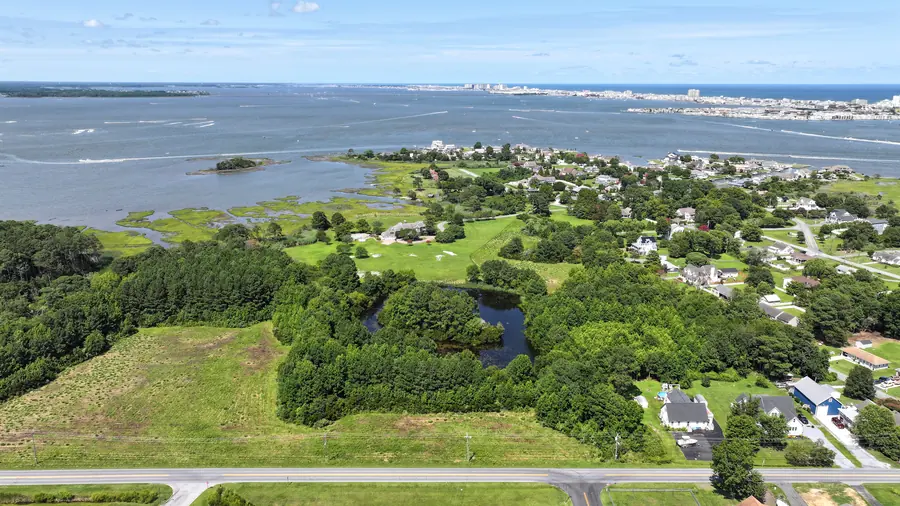 Aerial view over woods, a pond and open land toward Isle of Wight Bay and the Ocean City skyline