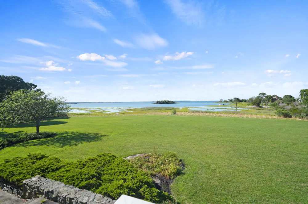 Open lawn running down to the marsh and Isle of Wight Bay under a blue sky